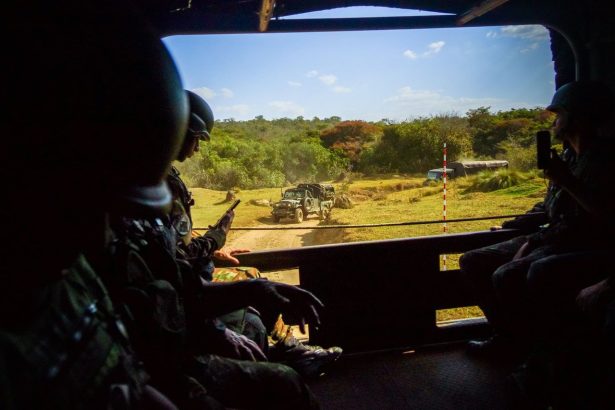 Militares observam uma atividade ao ar livre de dentro de um veículo blindado.