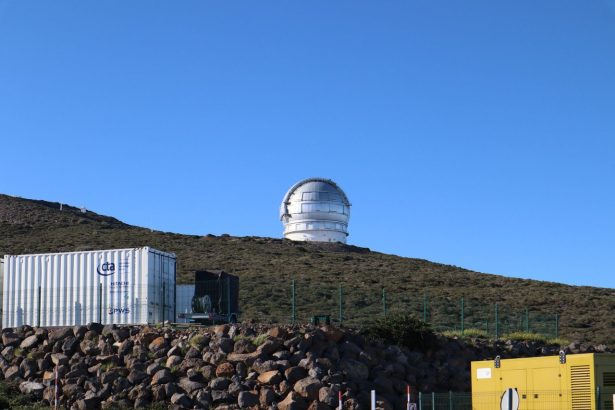 Grande cúpula de observatório científico situada no alto de uma colina sob céu azul.